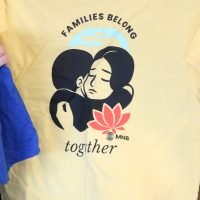 yellow t-shirt that says, "Families Belong Together"