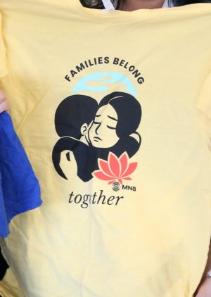 yellow t-shirt that says, "Families Belong Together"